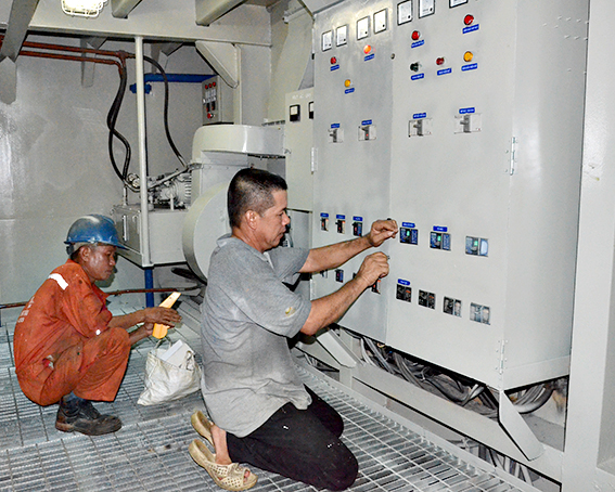 Thuyền viên kiểm tra hệ thống điều khiển điện trung tâm ở khoang máy tại tàu dịch vụ hậu cần thủy sản Gia Hân trước giờ ra khơi. Ảnh: THÀNH HUY